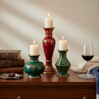 Hand-painted ruby red and emerald green ceramic candle holder set with warm candlelight